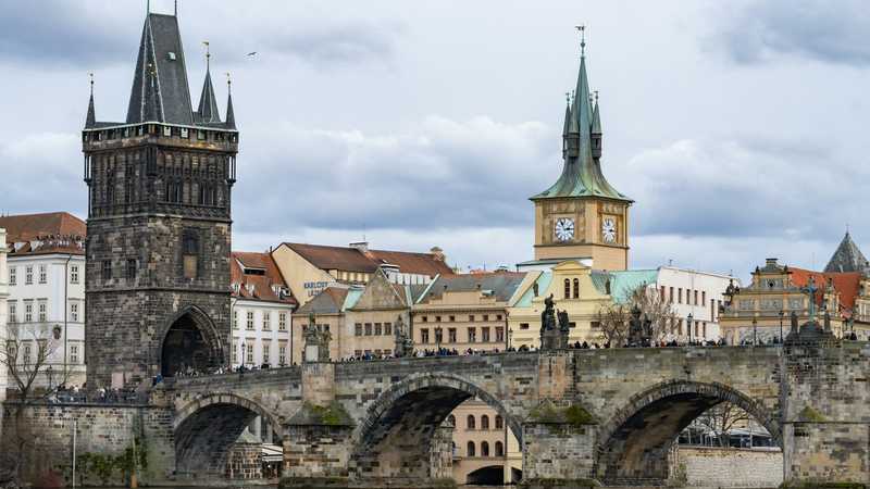 Podul Carol din Praga, cu turnul vechi și statuile, deasupra râului