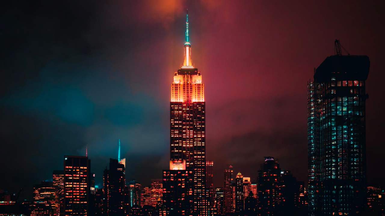 Skyline-ul din New York noaptea, cu Empire State Building luminat între alte clădiri
