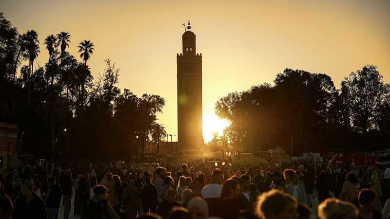 Apus peste piața Jemaa el-Fnaa din Marrakesh, cu minaretul moscheii Koutoubia și palmieri