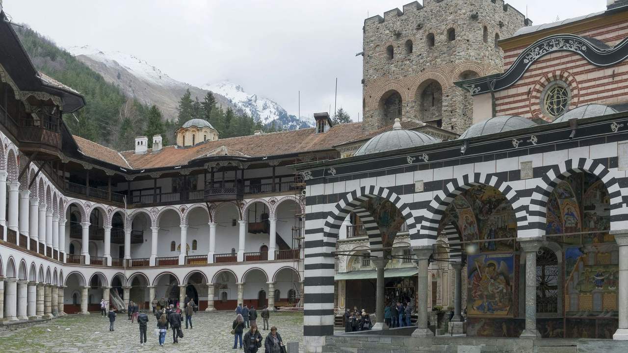 Mănăstirea Rila, cu ziduri și acoperișuri, în fața munților împăduriți din Bulgaria